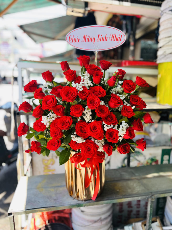 Giỏ hoa đẹp, lẳng hoa đẹp,giỏ hoa🌹 Mô tả giỏ hoa Giỏ hoa mang phong cách sang trọng, mạnh mẽ và đầy sức sống, được thiết kế theo tông đỏ rực rỡ chủ đạo, tượng trưng cho tình yêu, may mắn và niềm vui trọn vẹn — rất phù hợp để chúc mừng sinh nhật, khai trương, hay kỷ niệm đặc biệt. 🌸 Thành phần hoa Hoa hồng đỏ là điểm nhấn chính, được chọn lựa kỹ lưỡng với form tròn đều, cánh hoa dày và nở vừa phải, thể hiện sự quý phái, tự tin và rạng rỡ. Hoa baby trắng điểm xen kẽ, tạo nên sự tương phản nhẹ nhàng, giúp tổng thể trở nên hài hòa và tinh tế hơn. Lá xanh tươi làm nền, khiến sắc đỏ nổi bật và tự nhiên hơn. 🎀 Kiểu dáng và bố cục Giỏ hoa được cắm dạng hình chóp tròn, hoa được sắp xếp đều theo tầng lớp, tạo độ nở bung tự nhiên nhưng vẫn giữ sự cân đối. Bình hoa màu vàng ánh kim, phản chiếu ánh sáng nhẹ, mang đến cảm giác sang trọng và hiện đại. Phía trước được điểm tô thêm nơ lụa đỏ mềm mại, tăng thêm phần tinh tế và nổi bật. ✨ Tổng thể cảm nhận Giỏ hoa mang đến ấn tượng mạnh mẽ và quý phái, vừa đủ rực rỡ để thu hút, vừa đủ tinh tế để giữ nét sang trọng. Sắc đỏ tượng trưng cho niềm hân hoan, sự nồng nhiệt và thành công viên mãn, kết hợp cùng trắng tinh khôi, tạo nên bản hòa sắc cân bằng, trọn vẹn và đầy cảm xúc. Đây là một giỏ hoa thể hiện sự tôn trọng, lời chúc ý nghĩa và tinh thần tươi vui – thích hợp để gửi đến người thân, đối tác hoặc người đặc biệt trong dịp quan trọng.sinh nhật đẹp, giỏ hoa khai trương đẹp